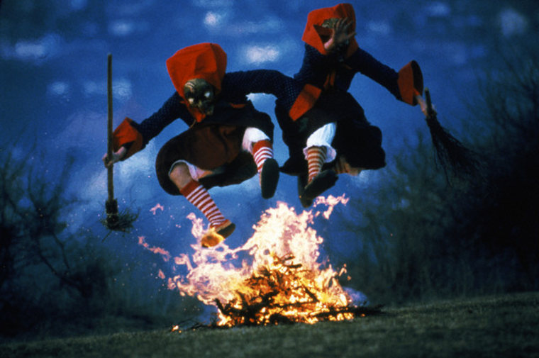 Two witches jumping over the camp fire.